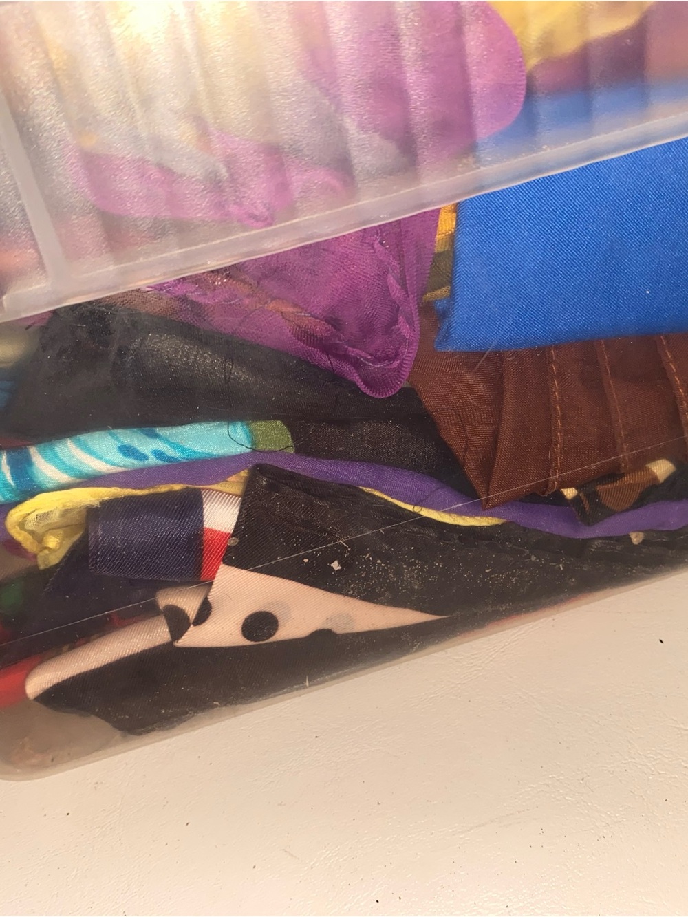 Clear Plastic Storage Bin with Visible Blue, Purple and Brown Fabrics